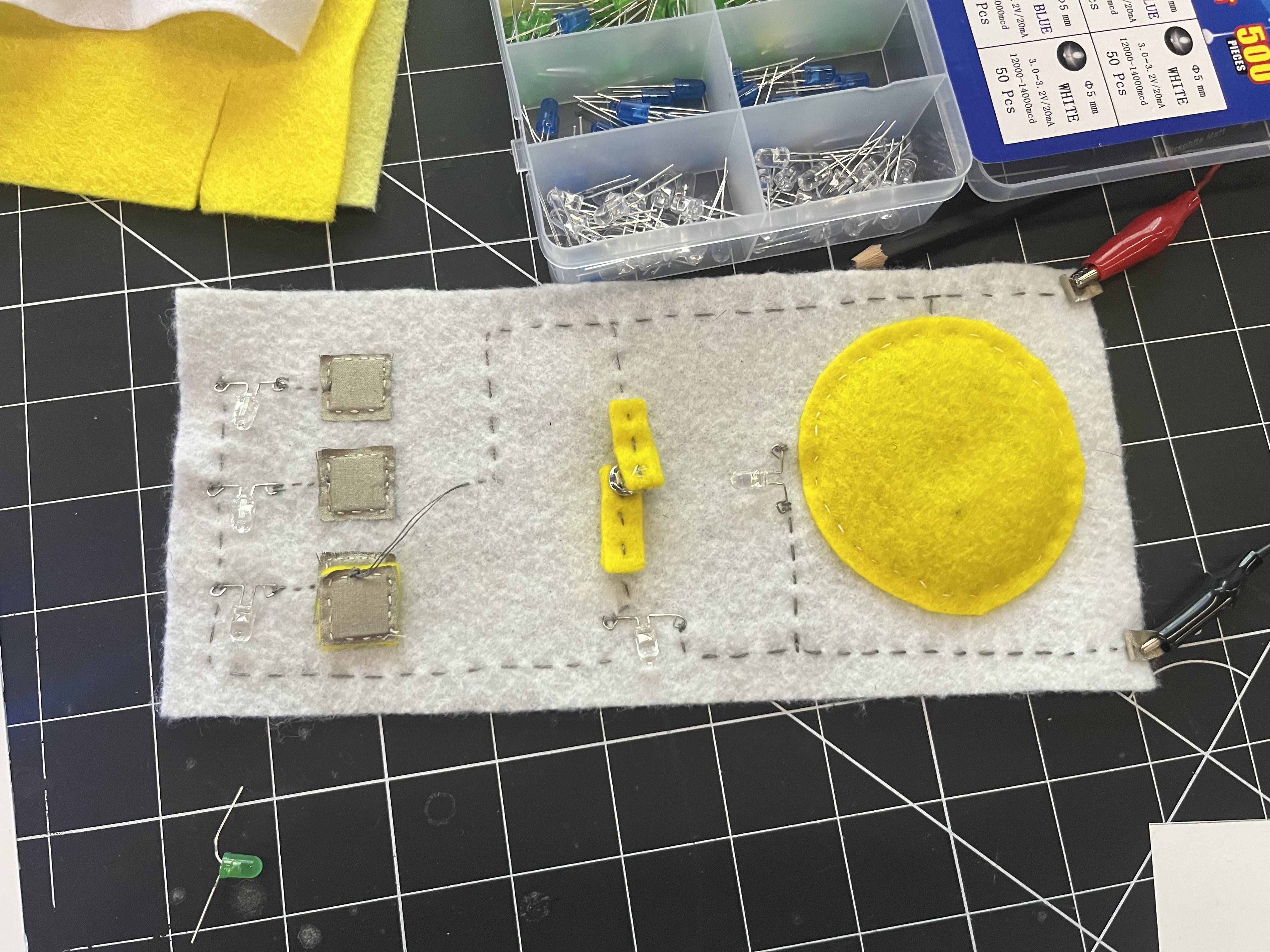 Experimenting with soft conductive materials, including conductive knit fabric and button-based switch systems.