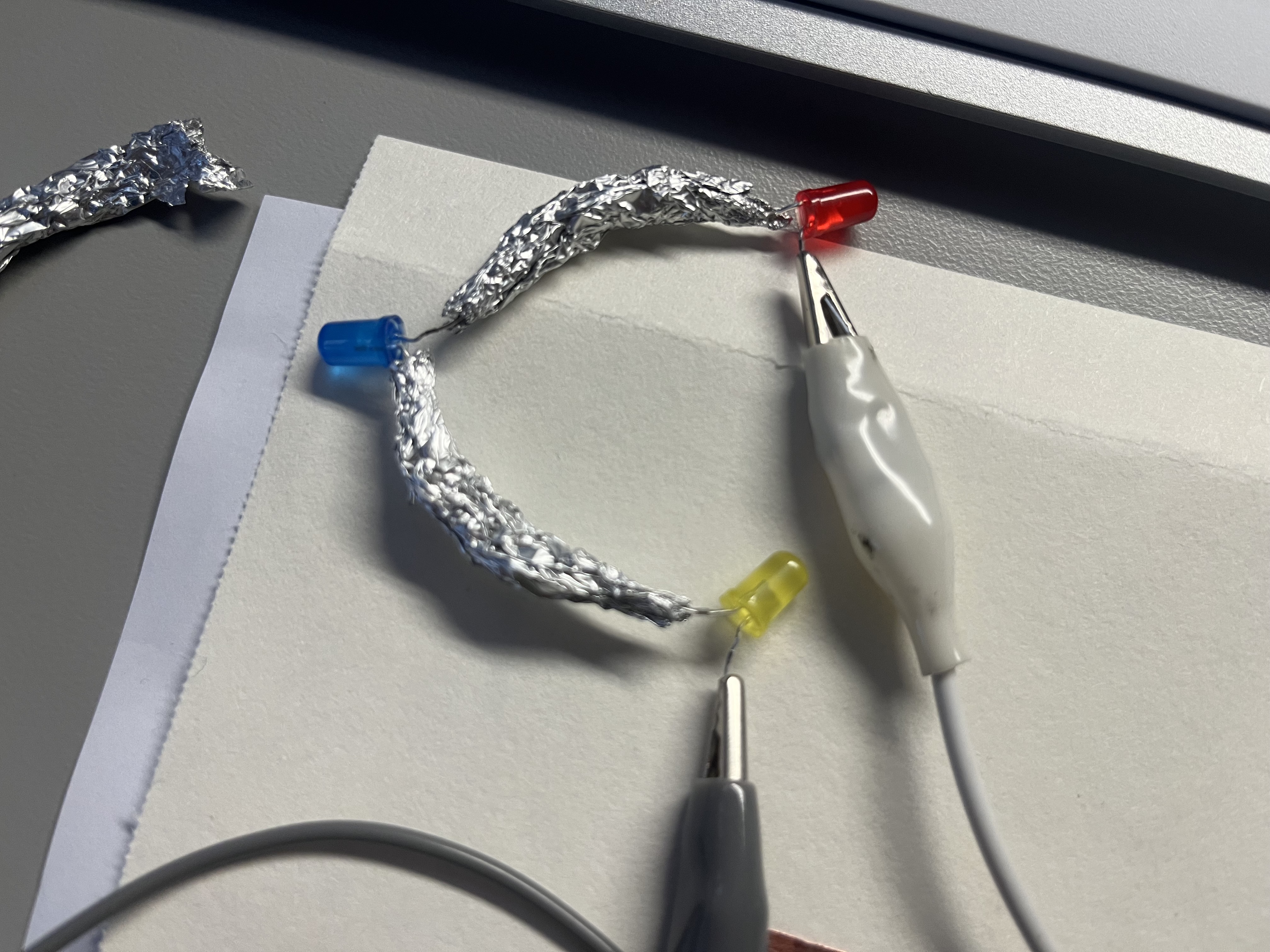 Building a three-bulb series circuit using aluminum foil connections.